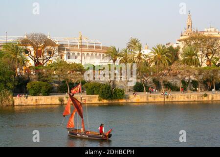 Vue sur la ville de Séville Espagne de l'autre côté de la rivière Guadalquiver Triana avec un petit bateau à voile et homme dans le traditionnel Vêtements avril Pâques 2014 Banque D'Images