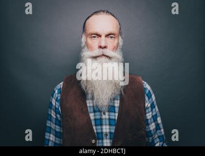 Portrait d'un homme âgé confiant avec une longue barbe blanche contre arrière-plan gris Banque D'Images