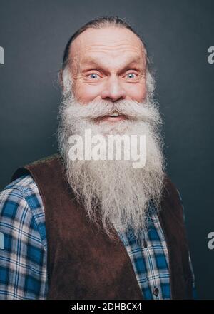 Portrait d'un homme âgé souriant avec une longue barbe blanche arrière-plan gris Banque D'Images