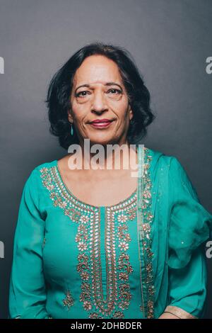 Portrait d'une femme âgée confiante portant du kameez de salwar sur du gris arrière-plan Banque D'Images