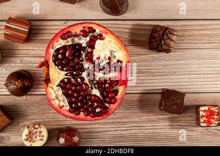 Posez-le sur une surface en bois, avec une demi-tranche de grenade fraîche et une variété de délicieux morceaux de chocolat éparpillés. Les pièces ont un luxe unique Banque D'Images