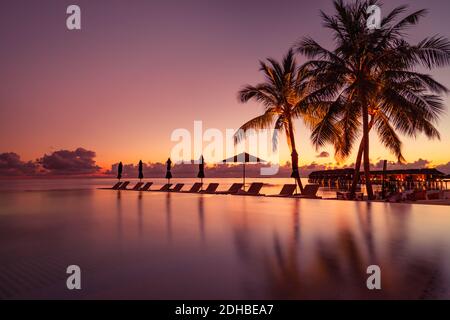 Magnifique piscine et coucher de soleil. Luxueux paysage tropical de plage, transats et chaises longues et réflexion sur l'eau. piscine de luxe sur la plage Banque D'Images