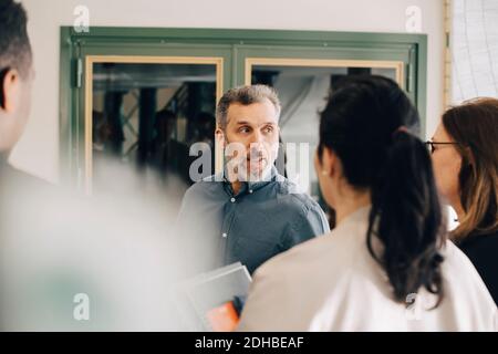 Homme d'affaires discutant avec des entrepreneurs multiethniques lors d'une conférence Banque D'Images