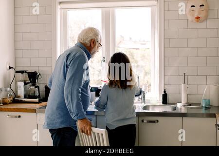 Grand-père et petite-fille debout au comptoir dans la cuisine Banque D'Images