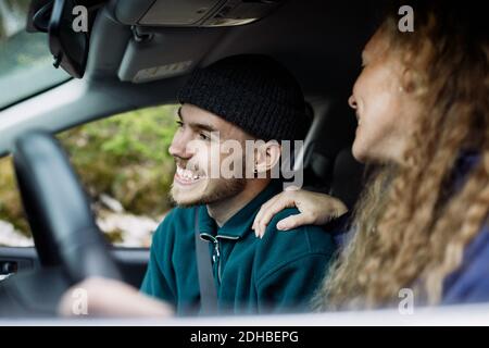Jeune femme parlant avec un ami souriant en voiture Banque D'Images