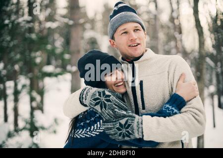 Des amis heureux s'embrassant en se tenant au parc pendant l'hiver Banque D'Images