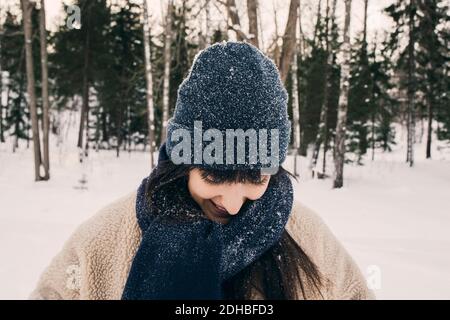 Femme mi-adulte souriante portant un chapeau en tricot et une écharpe pendant hiver Banque D'Images