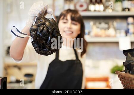 Femme souriante tenant des moules en magasin Banque D'Images