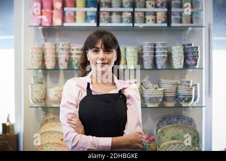 Portrait d'une vendeuse confiante debout avec les bras croisés contre la vaisselle à la boutique Banque D'Images