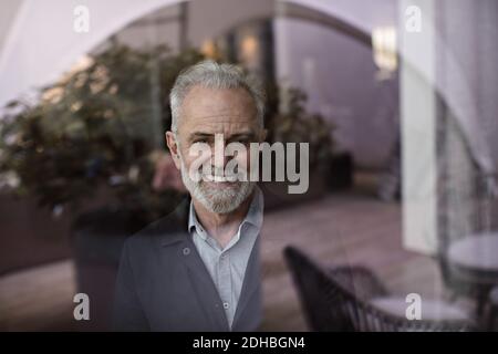 Portrait d'un homme d'affaires senior debout près d'une fenêtre au bureau Banque D'Images
