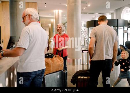 Famille souriante à la réception de l'hôtel Banque D'Images