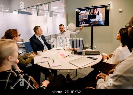 Professionnels en voyage d'affaires disposant d'une visioconférence dans la salle du conseil Banque D'Images