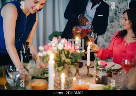 Milieu de section de l'homme verser la boisson à un ami à la table de salle à manger en fête Banque D'Images