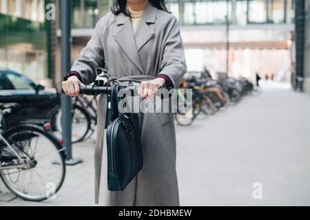 Milieu de section de femme d'affaires à bord d'un scooter électrique sur la piste de marche ville Banque D'Images