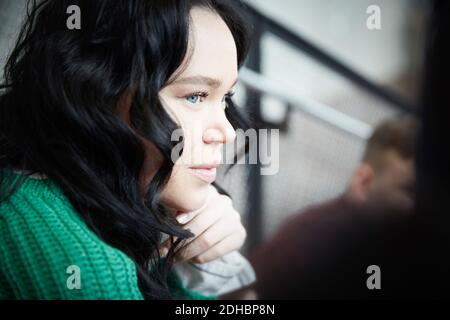 Gros plan de la jeune femme avec des cheveux noirs regardant loin dans université Banque D'Images