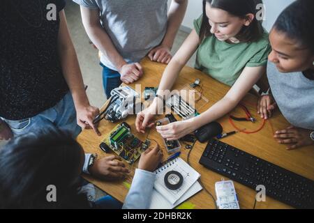Vue d'ensemble des élèves multiethniques du secondaire préparant la science projection au bureau en salle de classe Banque D'Images