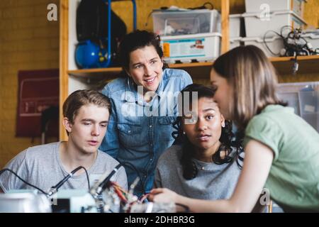 Les adolescentes multiethniques discutent avec une enseignante mature de la science projet en classe à l'école secondaire Banque D'Images