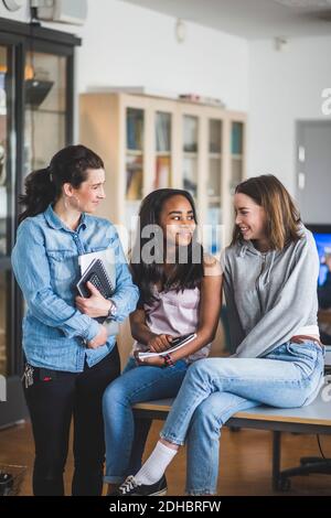 Femme souriante enseignant regardant les élèves du secondaire assis bureau dans le laboratoire informatique Banque D'Images