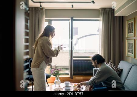 Couple dans la chambre d'hôtel, femme prenant une photo du plateau de petit déjeuner Banque D'Images