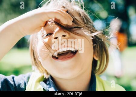 Portrait d'un garçon gai avec des cheveux tenoués dans l'aire de jeux Banque D'Images