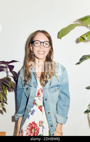 Portrait d'une jeune femme souriante debout contre le mur blanc à accueil Banque D'Images