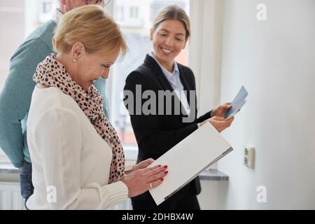 Agent souriant regardant un couple senior avec une brochure décidant de la couleur échantillons pour nouvelle maison Banque D'Images