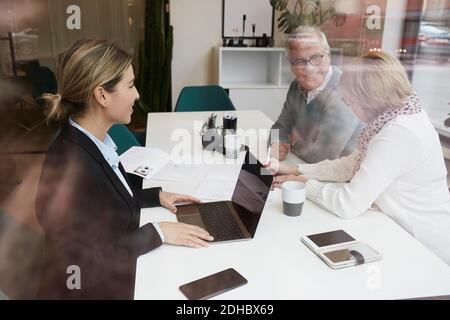 Une femme agent immobilier discutant avec un couple senior des documents de propriété au bureau Banque D'Images