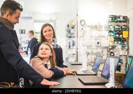 Famille discutant en se tenant dans un magasin d'ordinateur Banque D'Images