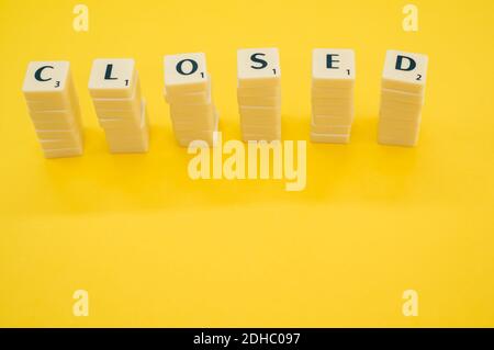 Les six piles de blocs de lettres blanches formant le mot FERMÉ sur fond jaune Banque D'Images