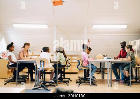 Enseignants de sexe masculin et féminin enseignant les élèves en classe à l'école Banque D'Images