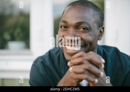Portrait d'un homme adulte moyen souriant avec les mains jointes Banque D'Images
