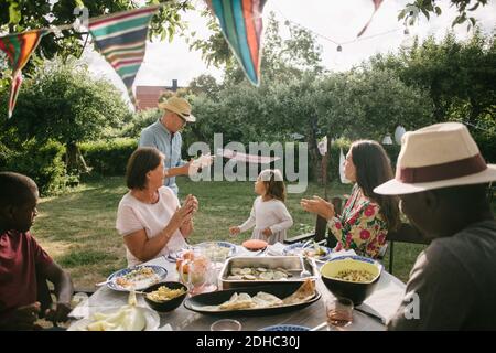 La famille applaudit à la danse de l'homme et de la fille pendant le jardin fête Banque D'Images