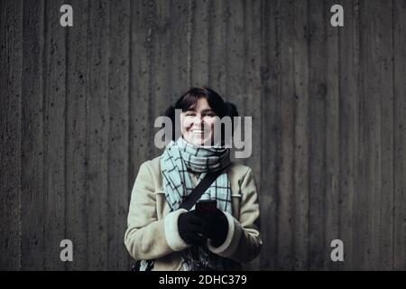 Portrait d'une jeune femme gaie portant des vêtements chauds debout contre le mur dans le métro Banque D'Images