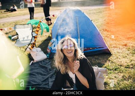 Vue en grand angle d'une femme gaie portant des lunettes de soleil tente sur le terrain en été Banque D'Images