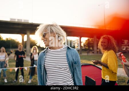 Un jeune homme souriant s'amusant avec des amis lors d'un événement musical jour ensoleillé Banque D'Images