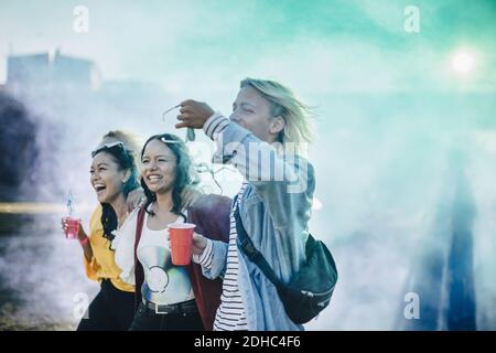 Des amis joyeux se promenant au milieu de la peinture en poudre à festival de musique Banque D'Images