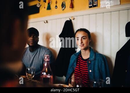 Jeune femme assise par l'homme tout en regardant une amie féminine au restaurant pendant le dîner Banque D'Images