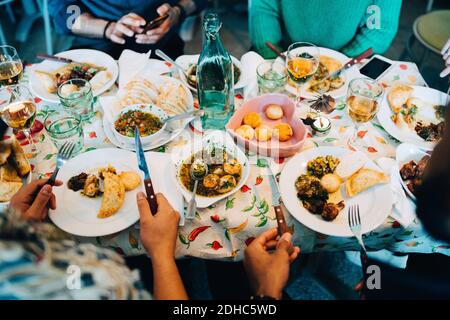 Milieu de jeunes amis multi-ethniques qui mangent le déjeuner au restaurant pendant fête Banque D'Images