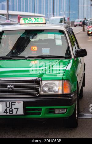 Taxi vert de Hong Kong. Le panneau de taxi éclairé sur le toit du taxi indique que le taxi est libre et disponible à embaucher Banque D'Images