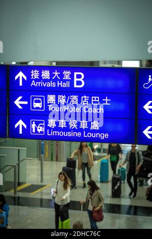 Le panneau des arrivées et départs de l'aéroport de Hong Kong s'affiche avec les passagers Banque D'Images