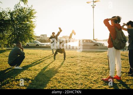 Des amis qui regardent un adolescent se tenir debout sur le terrain sous le soleil jour Banque D'Images