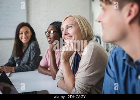 Des hommes d'affaires multiethniques souriants écoutent la salle de conférence pendant la réunion Banque D'Images