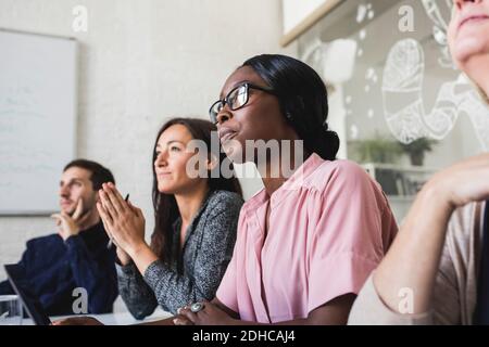 Des gens d'affaires créatifs écoutent pendant qu'ils sont assis dans la salle de conseil réunion Banque D'Images