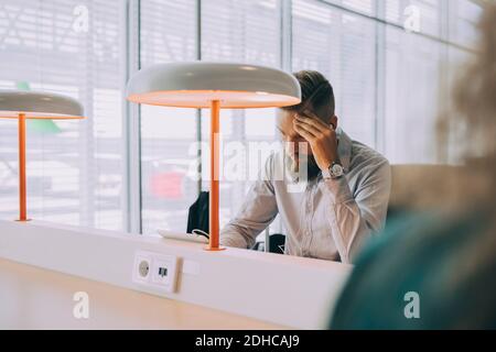 Homme d'affaires épuisé utilisant une tablette numérique tout en étant assis à la table zone de départ de l'aéroport Banque D'Images