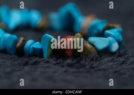 Un bracelet en pierres précieuses turquoise et autres pierres semi-précieuses colorées sur la surface grise Banque D'Images