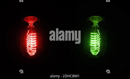 Ampoule rétro brillante sur fond sombre, fil lumineux visible en verre - version rouge et verte, mais la couleur peut être modifiée avec hue / satura Banque D'Images