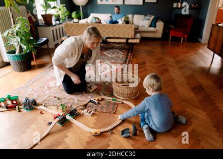 Mère regardant la fille jouer avec le train dans la vie chambre Banque D'Images