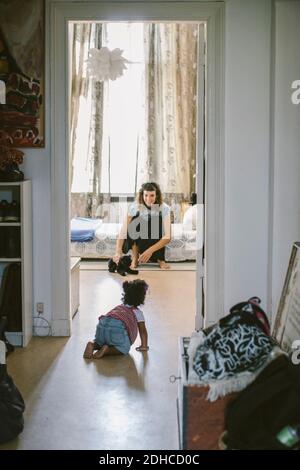 Bébé fille rampant vers la mère à la maison Banque D'Images