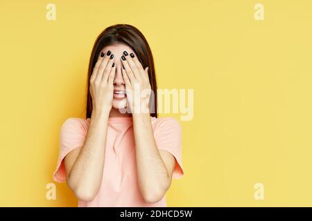 Bonne femme excitée face à face près par les mains attendant la surprise sur fond jaune Banque D'Images