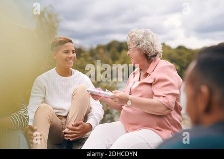 Grand-mère souriante donnant un cadeau à petit-fils dans le parc pendant le pique-nique Banque D'Images